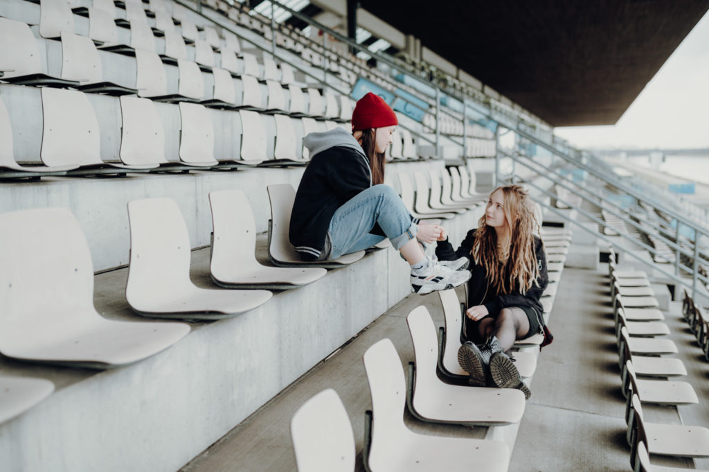 Händchenhaltendes Paar sitzt auf einer Tribühne und sieht sich in die Augen | Paarbilder in Oberschleißheim | Fotografin im raum FFB Landsberg Ammersee München