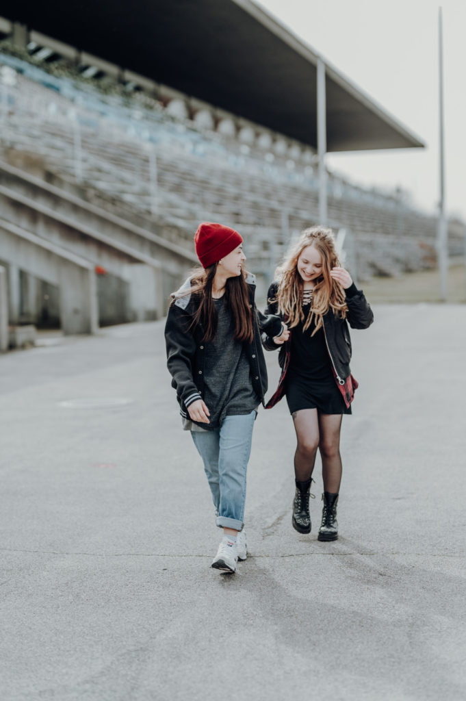 Pärchenshooting an der Ruderregatta in München. Lesbisches Paar läuft händchenhaltend | Fotografin in der Region München Ammersee Fürstenfeldbruck