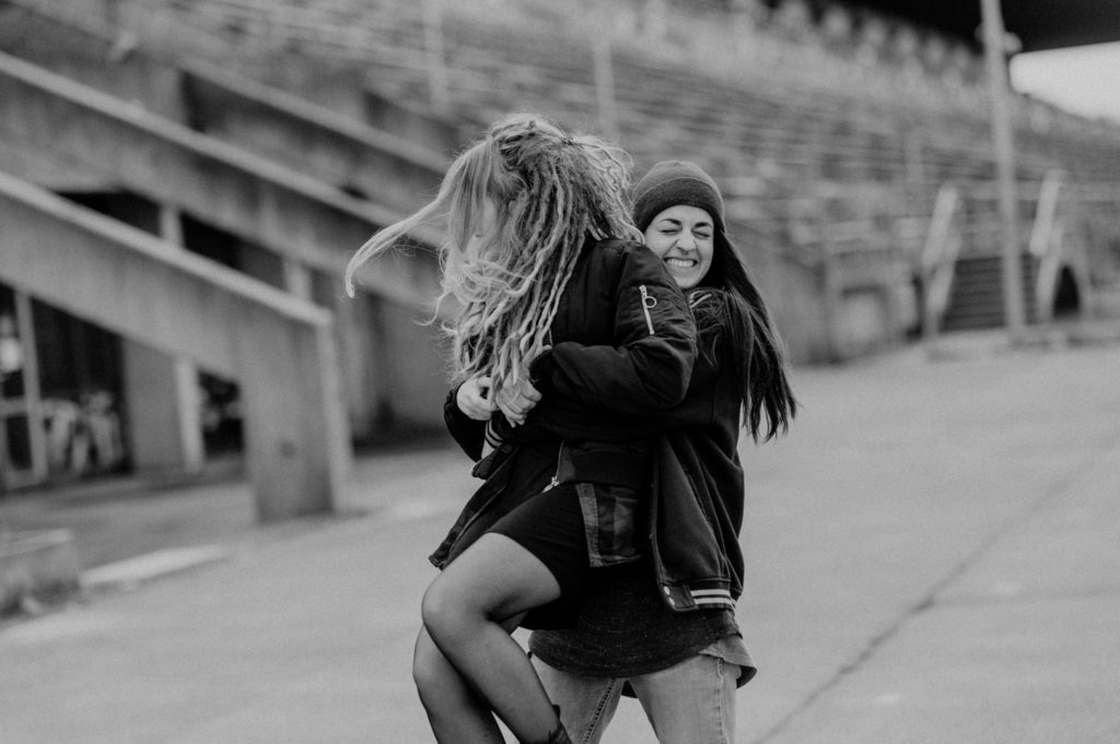 Pärchenshooting an der Ruderregatta in München. Lesbisches Paar läuft händchenhaltend | Fotografin in der Region München Ammersee Fürstenfeldbruck