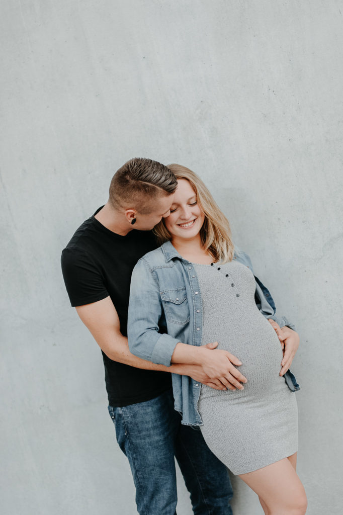 Lachendes Paar bei einem Babybauchshooting in München.
