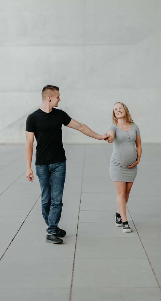 Lachendes Paar bei einem Babybauchshooting in München.