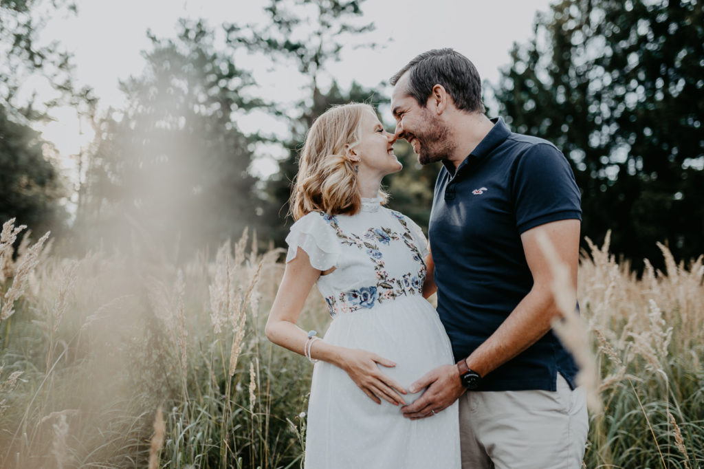 Lachendes Paar bei einem Babybauchshooting in München.