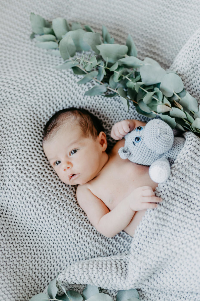 Newbornfotografie. Kind liegt in einem mit Fell ausgelegten Körbchen und schläft.