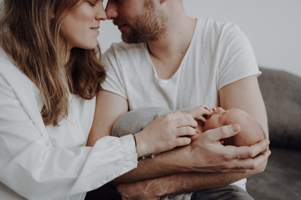 Familienbild von junger Familie mit Neugeborenen.